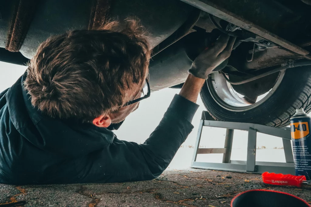 Photographie d'un garagiste sous une voiture